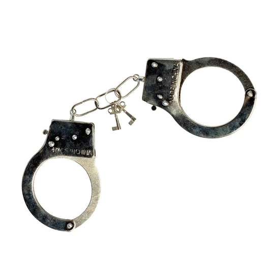 Metallische Handschellen mit Strasssteinen und zwei Schlüsseln, glänzend und robust.