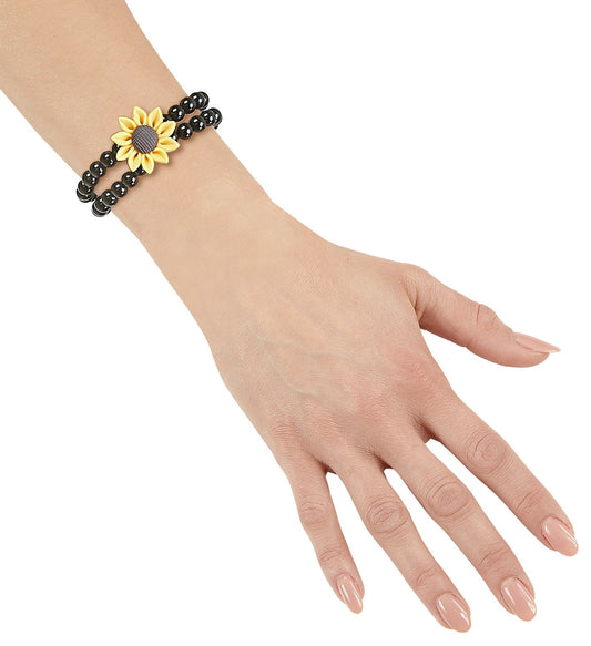 Black beaded bracelet with yellow sunflower charm on wrist.