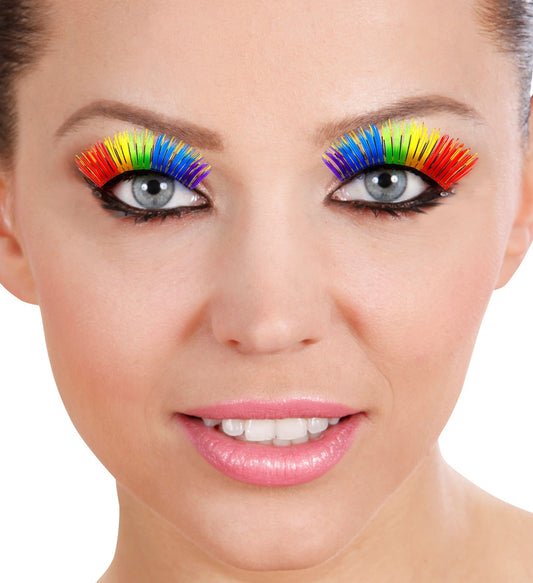 Woman with rainbow-colored false eyelashes applied, smiling on white background.