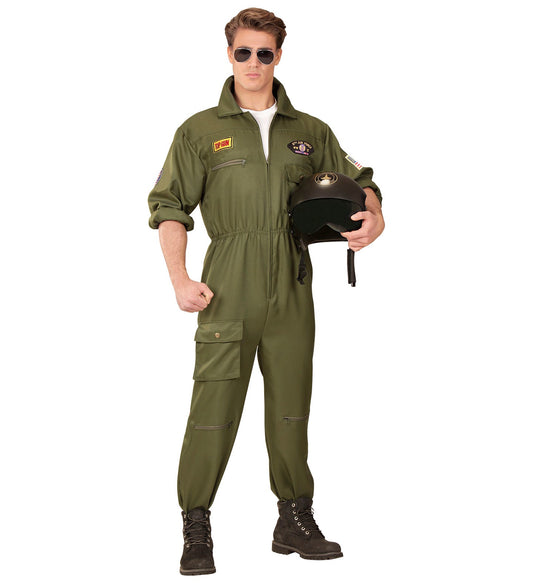 Man in green Top Gun flight suit holding black helmet, standing confidently.