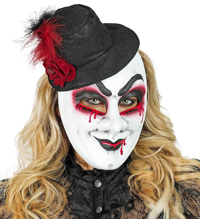 Blutige Commedia dell'Arte Maske mit Hut auf schwarzem Hintergrund