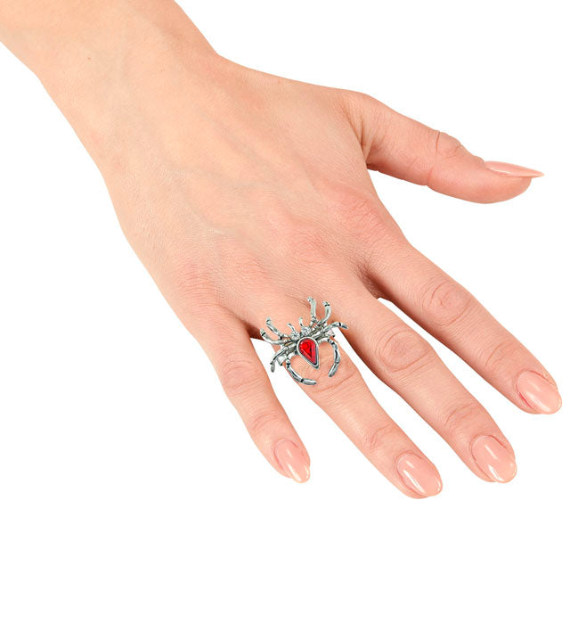 Spinnenring mit rotem Edelstein und funkelndem Strass auf schwarzem Hintergrund