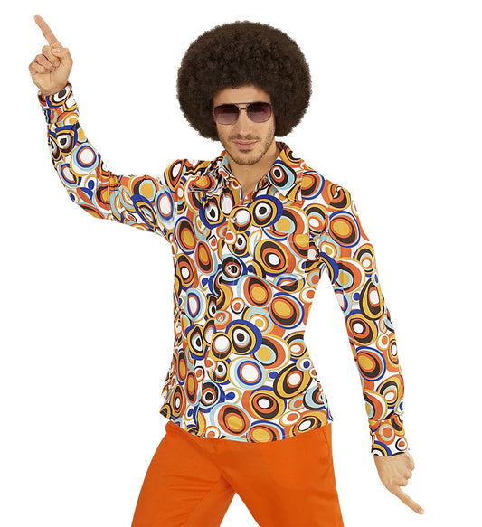 Man in 70s afro wig and sunglasses wearing colorful bubble-print disco shirt and orange pants.