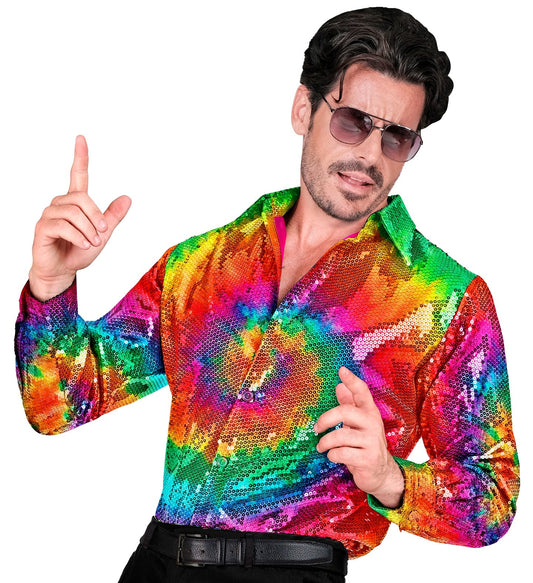 Man in rainbow sequin tie-dye shirt posing with one finger raised.