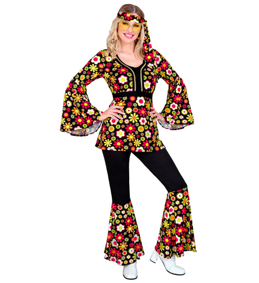 Frau in Widmann Hippie-Kostüm mit Blumen-Oberteil, Schlaghose und Stirnband.