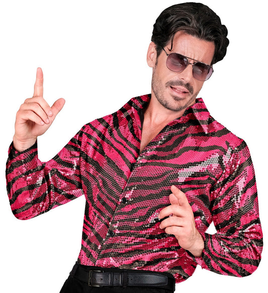 Mann in reversiblem pink-silbernem Paillettenhemd mit Zebralook, Finger zeigt nach oben.