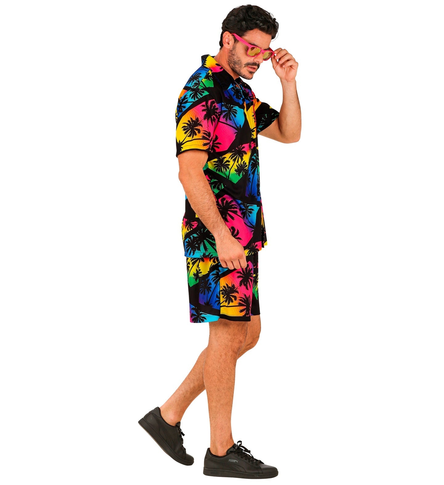 Man in dark tropical print shirt and shorts with neon accents, walking side view.
